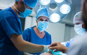 Surgeon looking at camera while colleague performing operation in operation room