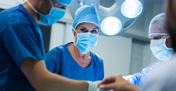 Surgeon looking at camera while colleague performing operation in operation room